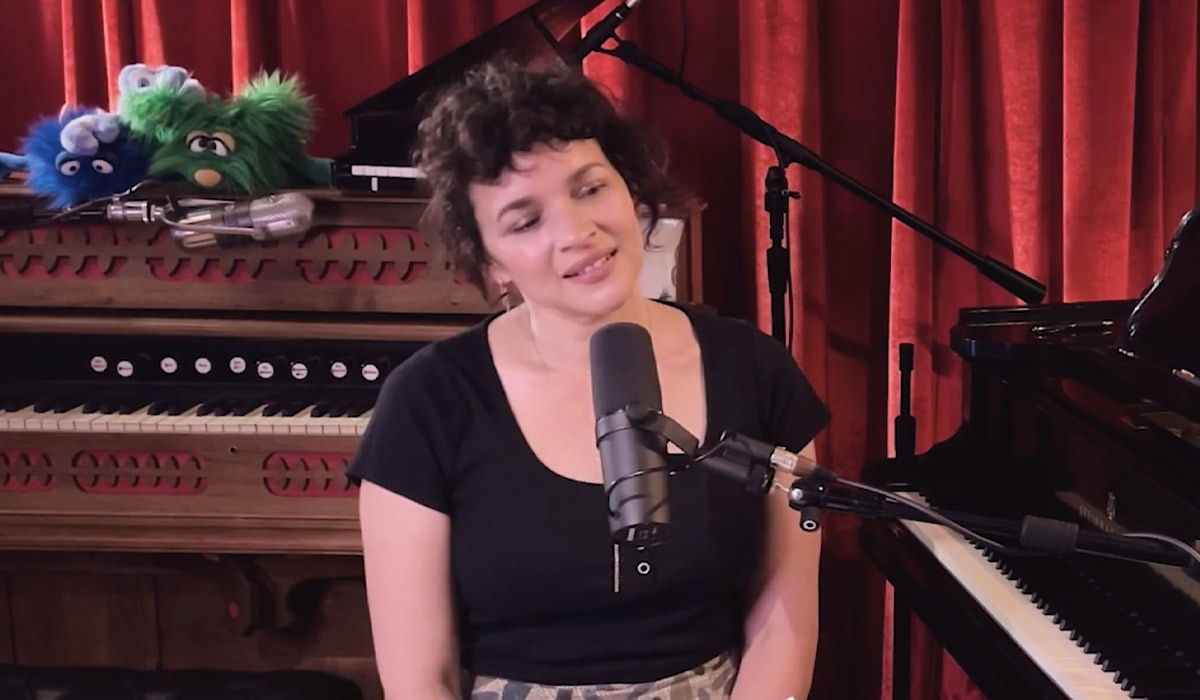 Norah Jones at the piano before a red studio curtain